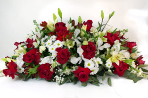 Centro de condolencias con floraciones blancas y rosas rojas