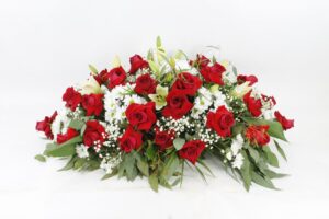 Centro de condolencias con floraciones blancas y rosas rojas