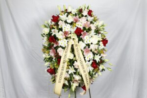 Corona de condolencias, posición vertical, con floraciones tono pastel y rosas blancas y rojas Nº1