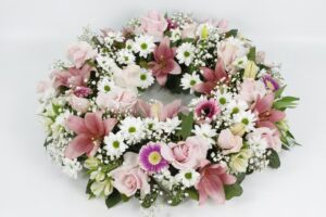 Corona de condolencias posición horizontal, floraciones en tonos pastel y rosas blancas y rosas