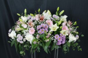 Centro de condolencias con rosas y floraciones blancas y rosas,