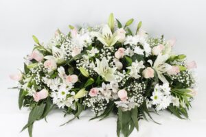Centro de condolencias con rosas y floraciones color blanco y rosa